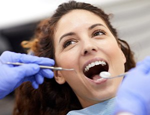 Woman with curly hair opening mouth for dental exam