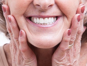 Nose-to-neck image of woman placing hands on the sides of her face