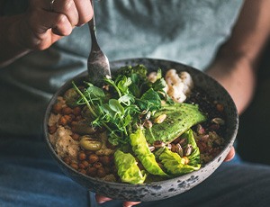 Hands holding bowl of salad and fork