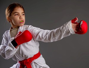 Girl in martial arts outfit with green mouthguard