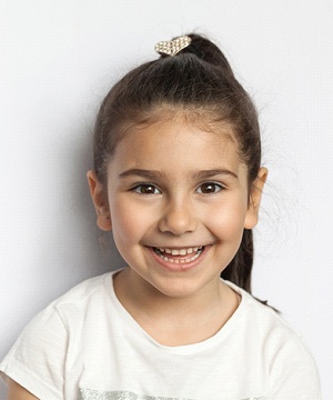 A little girl smiling in front of white background
