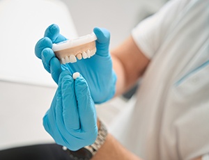 Dentist placing a dental crown on a mouth mold