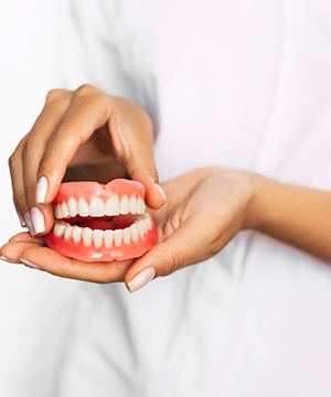dentist holding set of dentures in Virginia Beach
