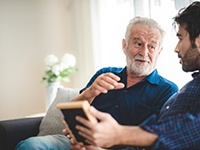 An older man talking with his son while sitting on a couch