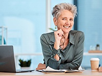 A smiling, mature business woman sitting at a desk