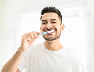 Man in white shirt brushing his teeth