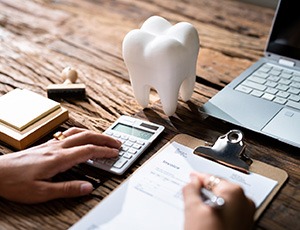 Patient calculating cost on desk with prop tooth
