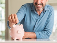 man putting coins into a pink piggy bank 