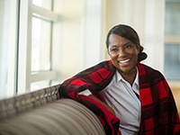 A middle-aged woman wearing a plaid shawl and smiling after receiving financial help for her dental implants