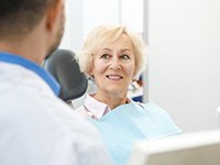 An older woman smiles while she listens to her dentist