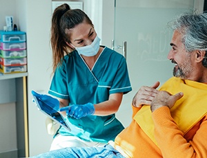Implant dentist in Virginia Beach explaining treatment to older patient