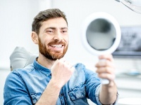 patient with dental implants in Virginia Beach admiring his new smile in a mirror