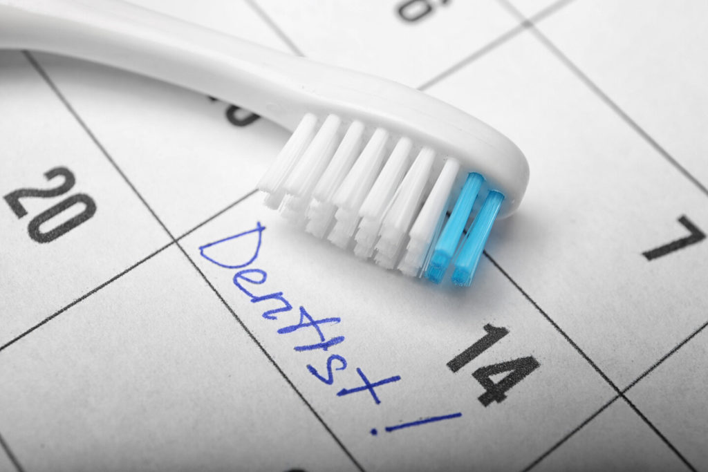 calendar with reminder to visit dentist and toothbrush