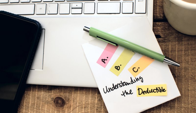 pen and pad with understanding the deductible on it